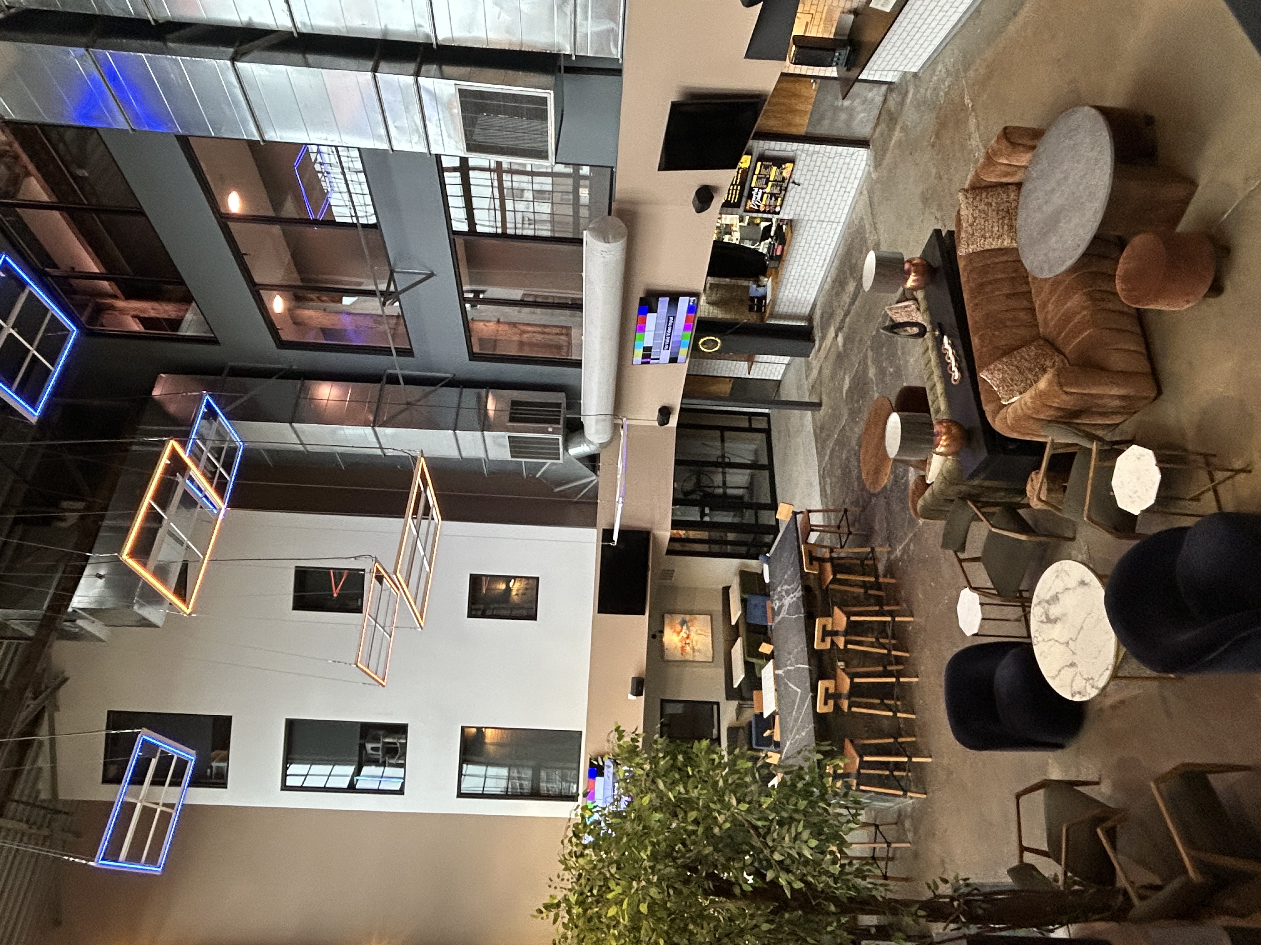 Overhead view of The Power House community lounge atrium with neon pendant lights, designer seating, and multi-story windows in Rock Hill, SC