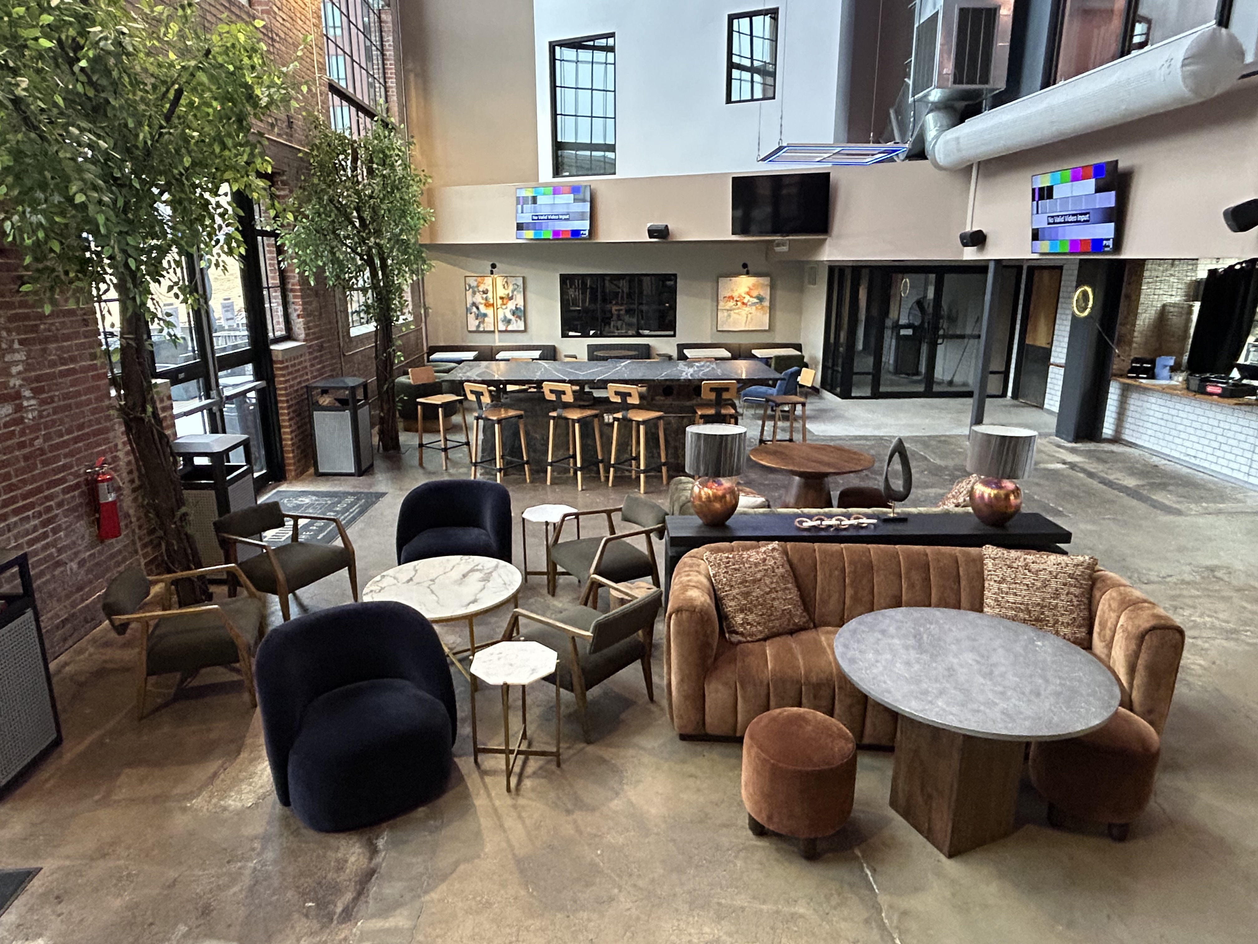 Floor-level view of The Power House community lounge with velvet sofas, marble accent tables, and a marble-top bar counter