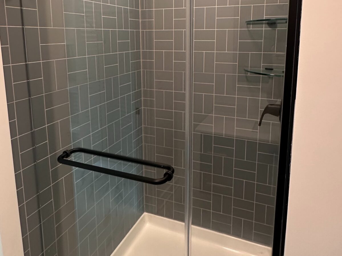 Modern bathroom with glass walk-in shower, quartz vanity, and black fixtures at a Power House Rock Hill luxury apartment