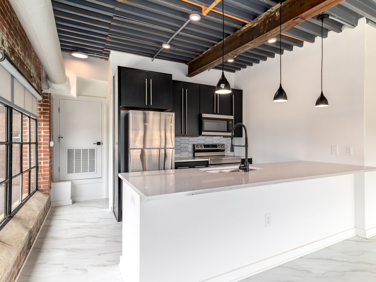 Luxury apartment kitchen with quartz countertops, black cabinetry, stainless appliances, and pendant lighting at The Power House Rock Hill